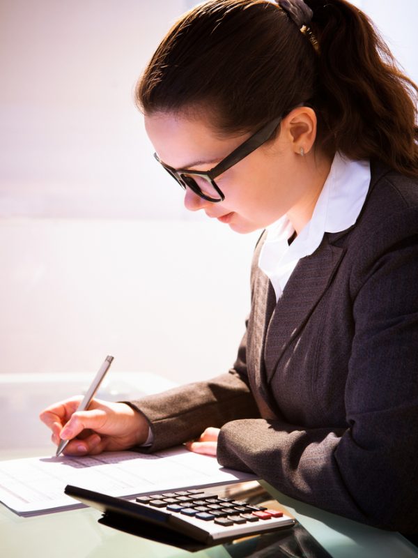 Young businesswoman calculating tax at desk in office